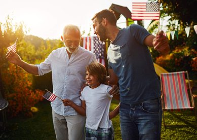 3 generations of men waving flags in their backyard